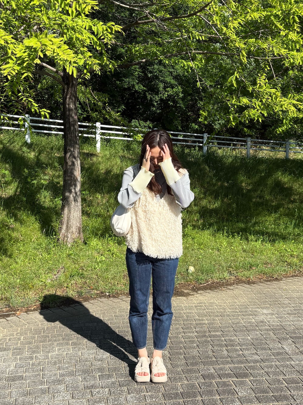 ベージュ系のベスト、グレー系のTシャツ/カットソー、ホワイト系のショルダーバッグを着用したレディースの春コーディネートの3枚目の写真