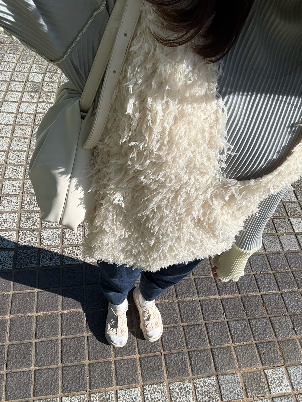 ベージュ系のベスト、グレー系のTシャツ/カットソー、ホワイト系のショルダーバッグを着用したレディースの春コーディネートの2枚目の写真