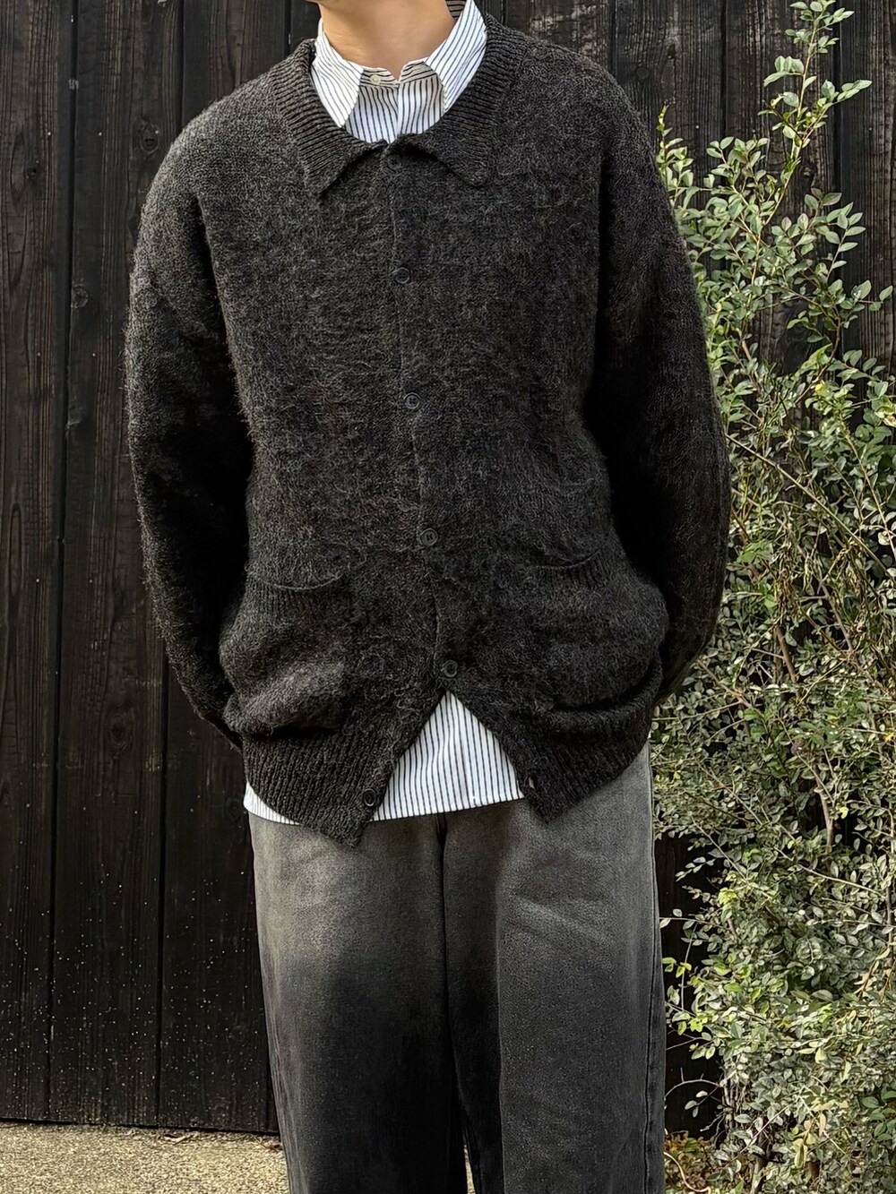 グレー系のカーディガン/ボレロ、グレー系のシャツ/ブラウス、ブラック系のデニムパンツを着用したメンズの秋コーディネートの2枚目の写真