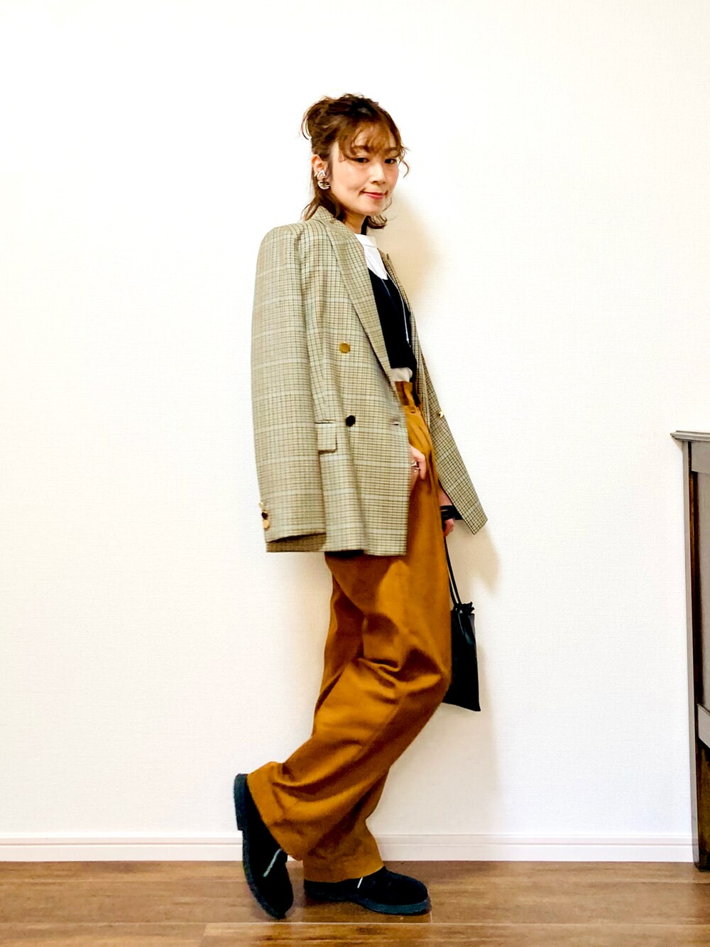 ベージュ系のテーラードジャケット、ブラック系のトップス、ブラウン系のデニムパンツを着用したレディースの冬コーディネートの4枚目の写真