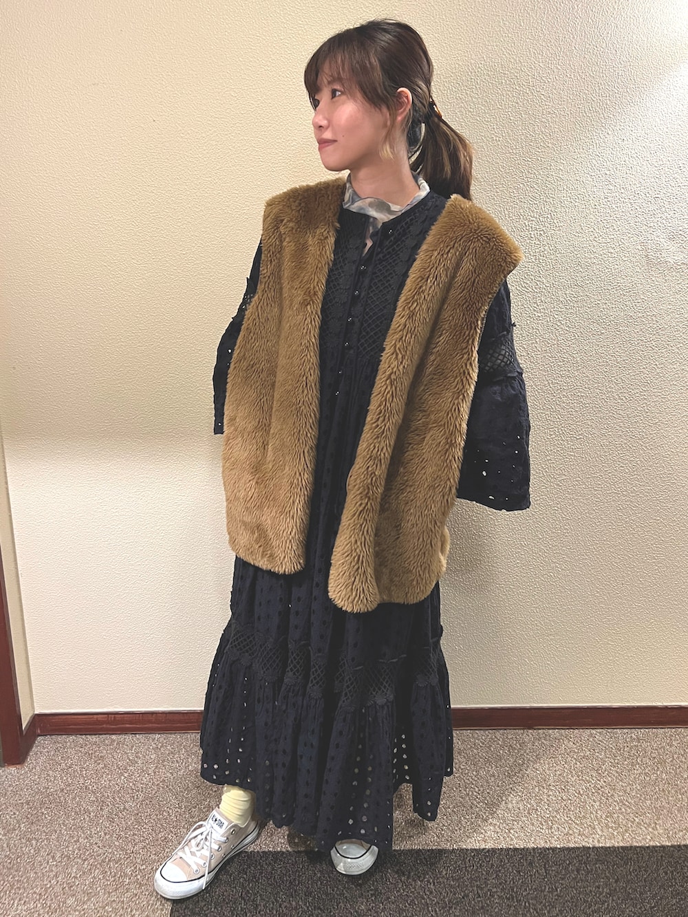 ベージュ系のスニーカー、ブラック系のワンピース、ブラウン系のベストを着用したレディースの春コーディネートの2枚目の写真