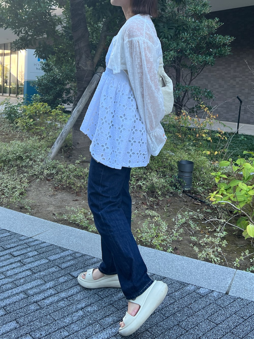 ブルー系のデニムパンツ、ベージュ系のサンダル、ブラウン系のバッグを着用したレディースの春コーディネートの2枚目の写真