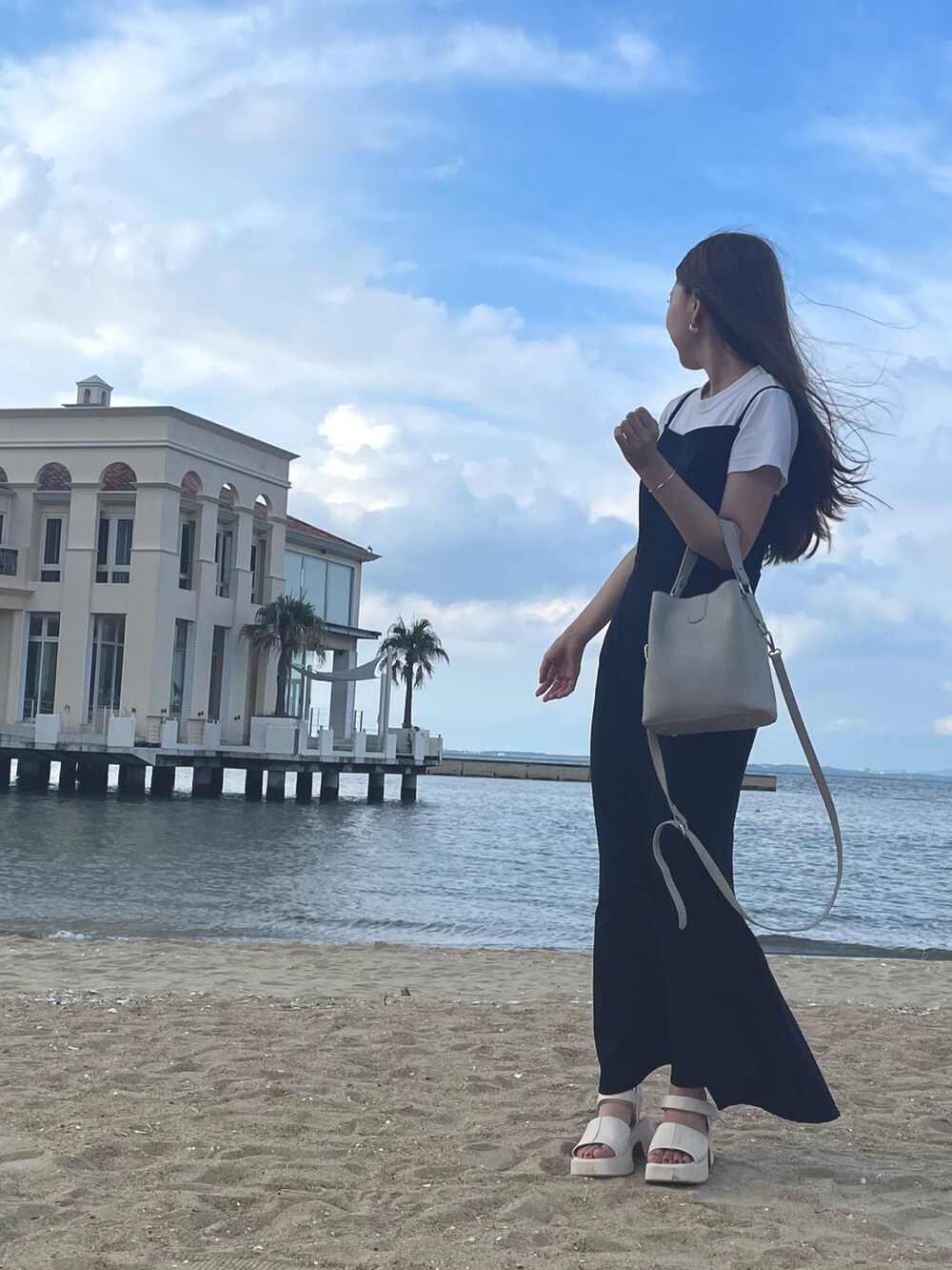 ブラック系のワンピース、ベージュ系のハンドバッグ、ホワイト系のTシャツ/カットソーを着用したレディースの夏コーディネートの2枚目の写真