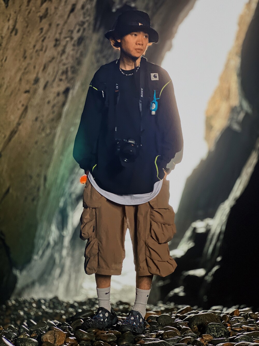 ブラック系のスウェット、ブラウン系のカーゴパンツ、ブラック系のスリッポンを着用したメンズの春コーディネートの4枚目の写真