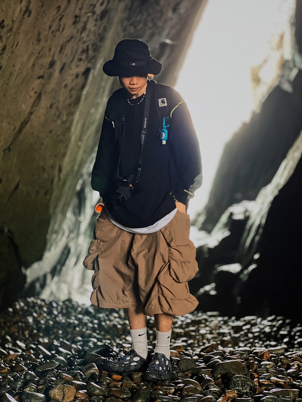 ブラック系のスウェット、ブラウン系のカーゴパンツ、ブラック系のスリッポンを着用したメンズの春コーディネートの2枚目の写真