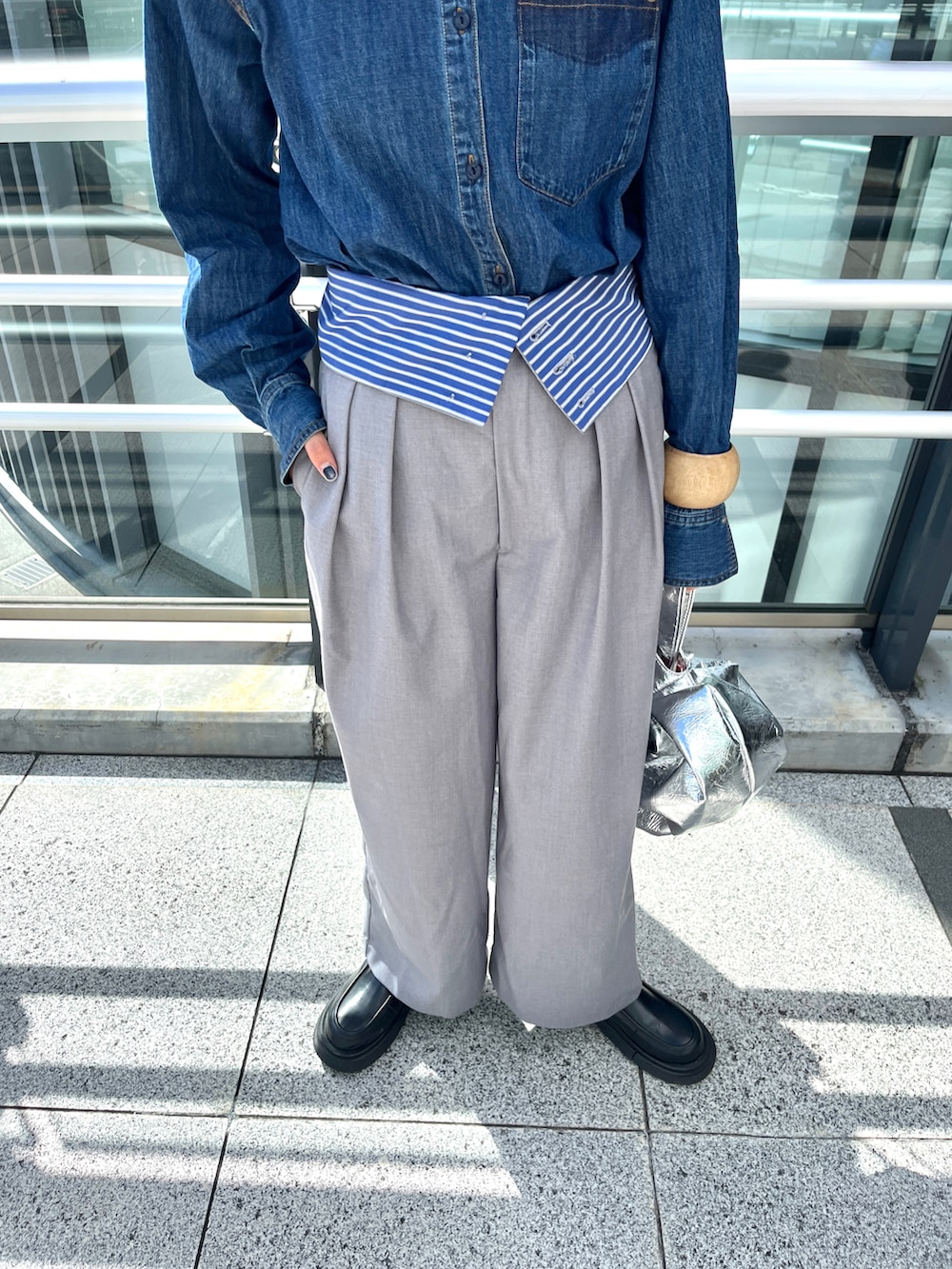 ブルー系のシャツ/ブラウス、グレー系のその他パンツ、ブラック系のブーツを着用したレディースの春コーディネートの2枚目の写真