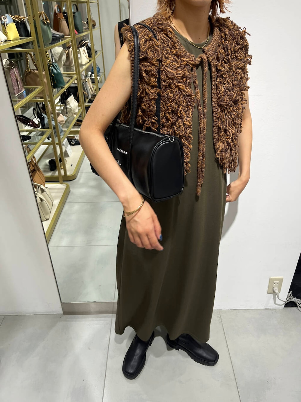 ブラウン系のベスト、ブラック系のブーツ、グリーン系のワンピースを着用したレディースの夏コーディネートの3枚目の写真