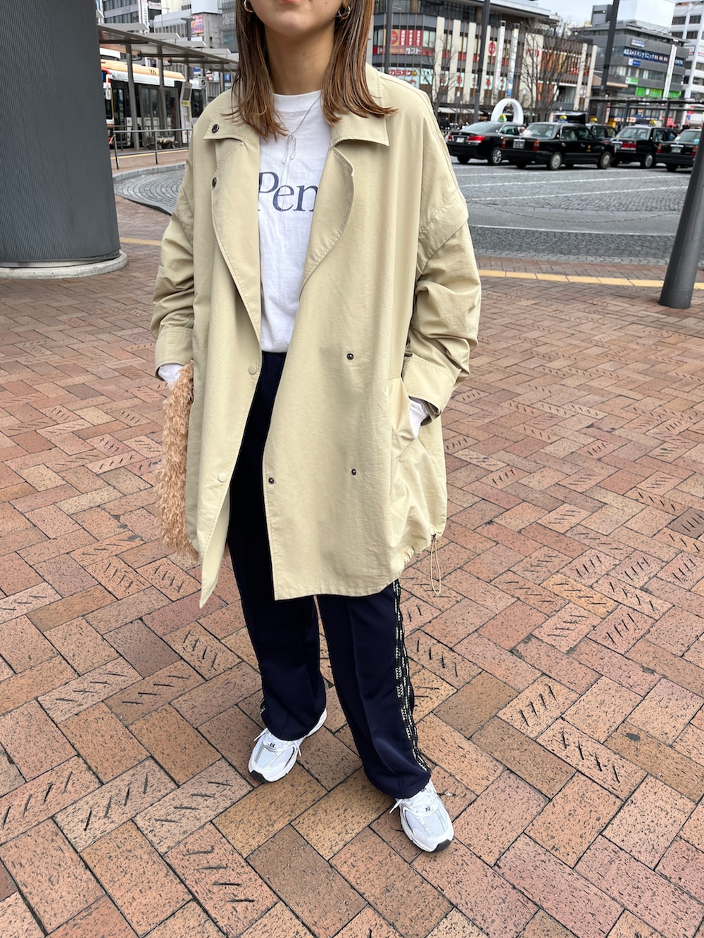 ベージュ系のポンチョ、ブルー系のその他パンツ、ホワイト系のスニーカーを着用したレディースの春コーディネートの2枚目の写真