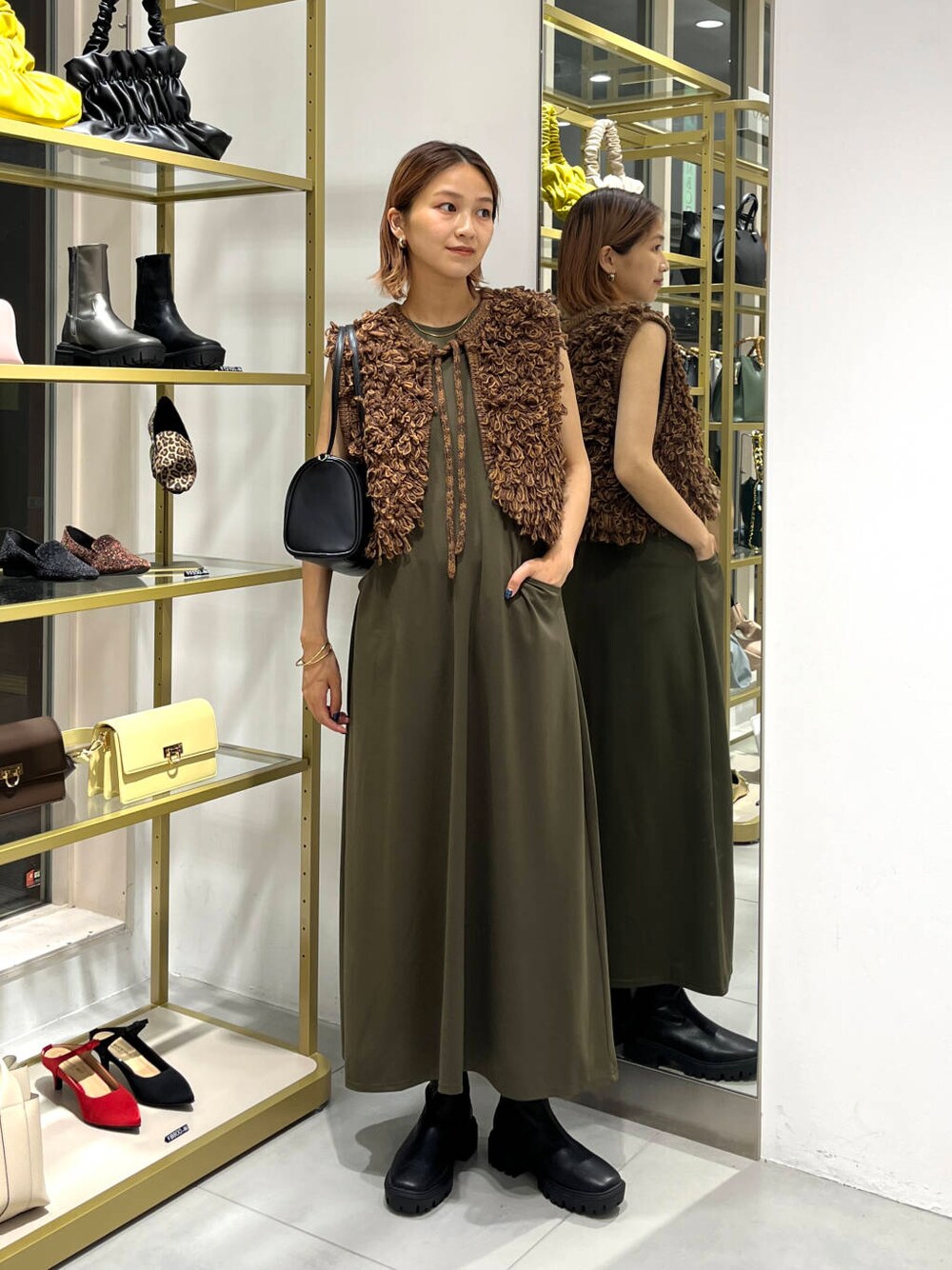 ブラウン系のベスト、ブラック系のブーツ、グリーン系のワンピースを着用したレディースの夏コーディネートの2枚目の写真