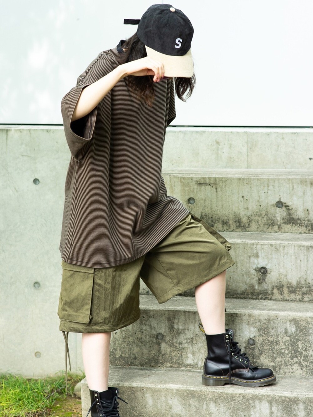 ブラウン系のTシャツ/カットソー、グリーン系のカーゴパンツ、ブラック系のブーツを着用したレディースの春コーディネートの2枚目の写真