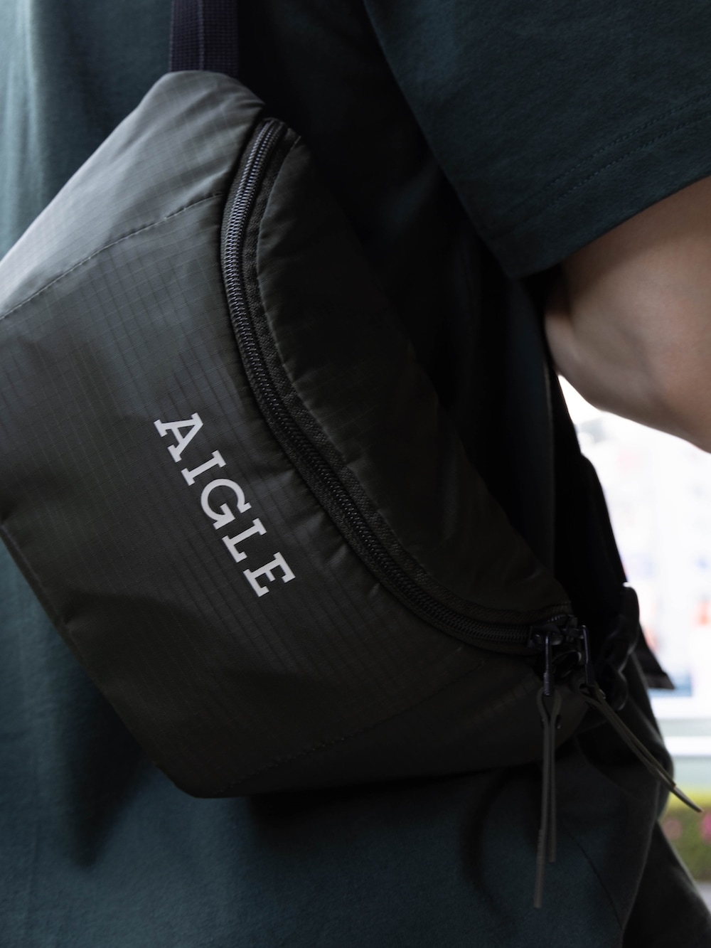 グリーン系のマウンテンパーカー、グリーン系のTシャツ/カットソー、グリーン系のボディバッグ/ウエストポーチを着用したメンズの夏コーディネートの4枚目の写真