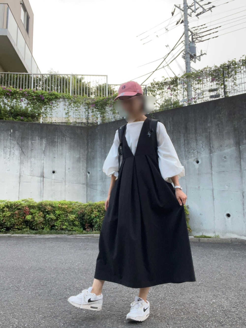 ブラック系のジャンパースカート、ホワイト系のシャツ/ブラウス、ホワイト系のスニーカーを着用したレディースの夏コーディネートの2枚目の写真