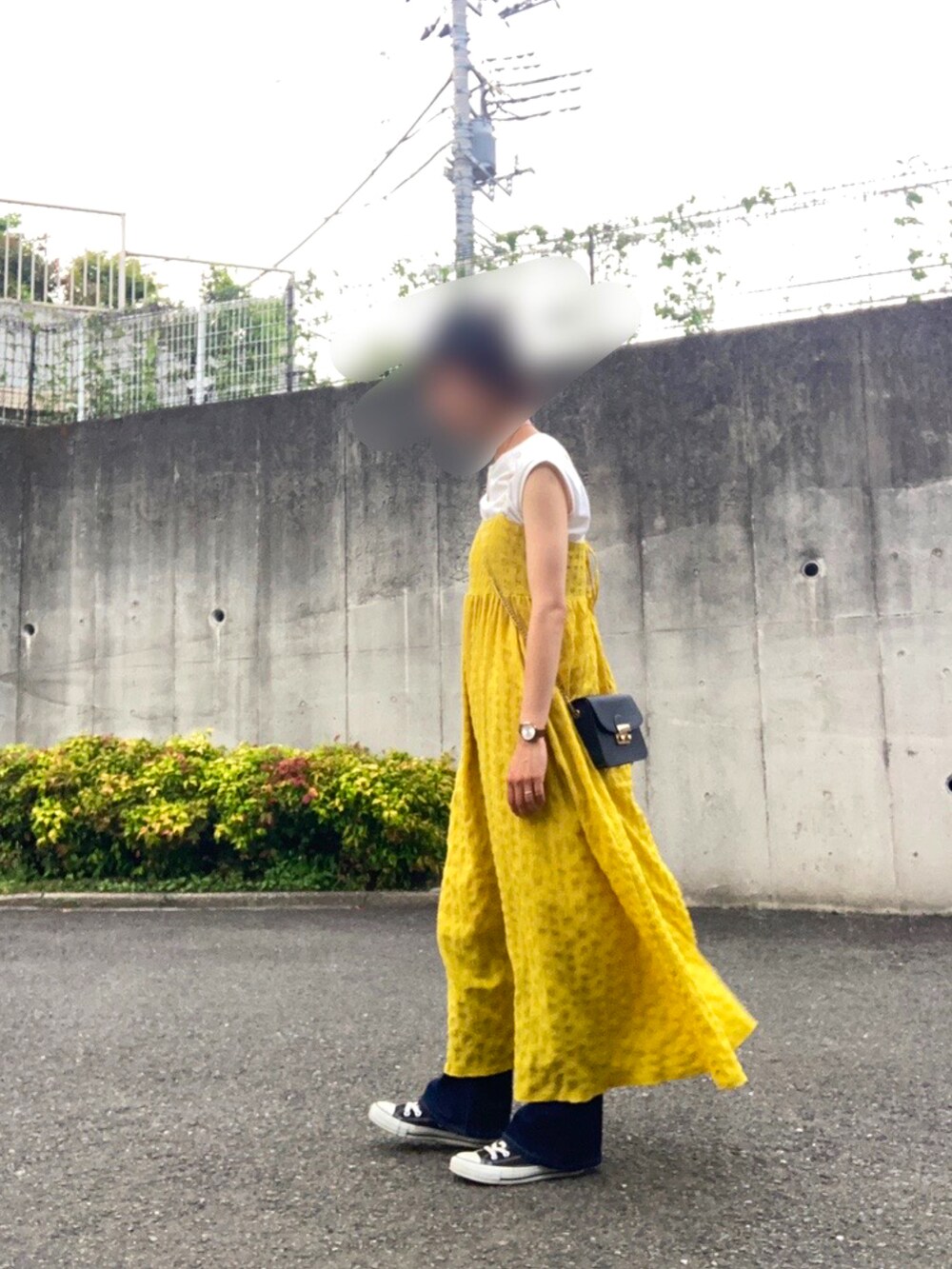 イエロー系のワンピース、ホワイト系のTシャツ/カットソー、ブルー系のデニムパンツを着用したレディースの春コーディネートの2枚目の写真