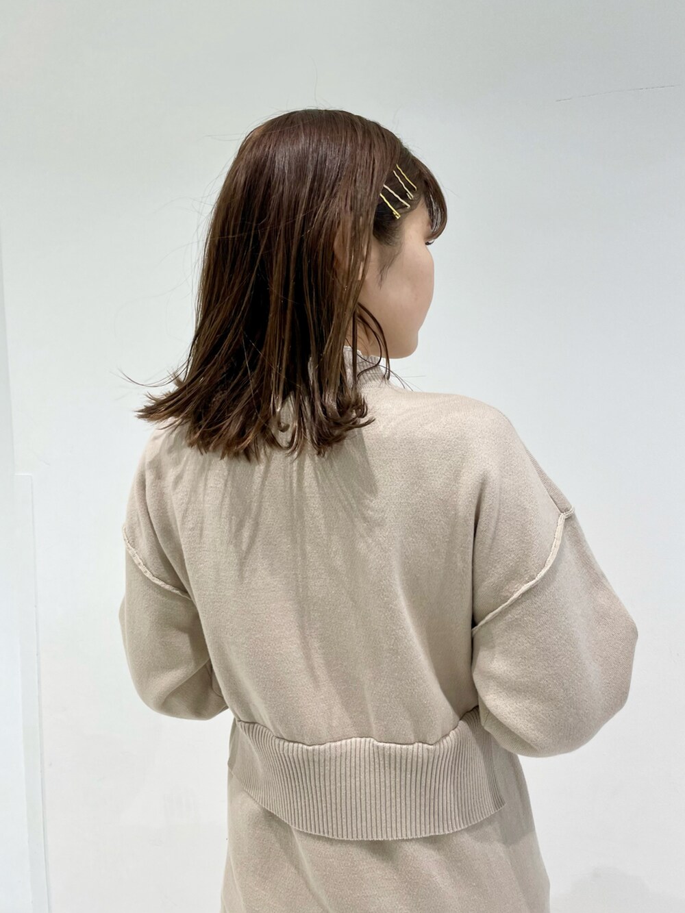 ベージュ系のワンピース、イエロー系のショルダーバッグ、ホワイト系のTシャツ/カットソーを着用したレディースの冬コーディネートの2枚目の写真