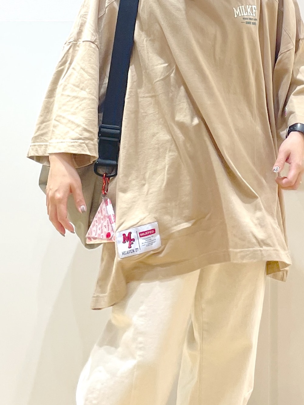 ベージュ系のTシャツ/カットソー、ベージュ系のショルダーバッグ、ホワイト系のデニムパンツを着用したレディースの春コーディネートの4枚目の写真