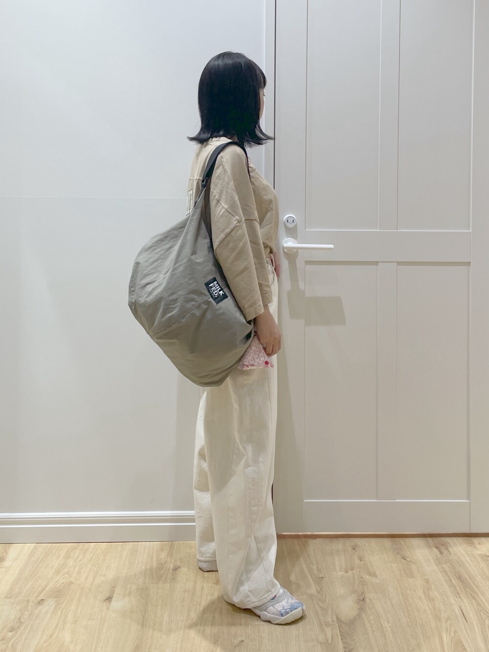 ベージュ系のTシャツ/カットソー、ベージュ系のショルダーバッグ、ホワイト系のデニムパンツを着用したレディースの春コーディネートの3枚目の写真