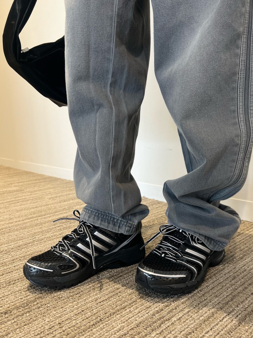 ブラック系のショルダーバッグ、ブラック系のスカート、ブルー系のデニムパンツを着用したレディースの冬コーディネートの2枚目の写真