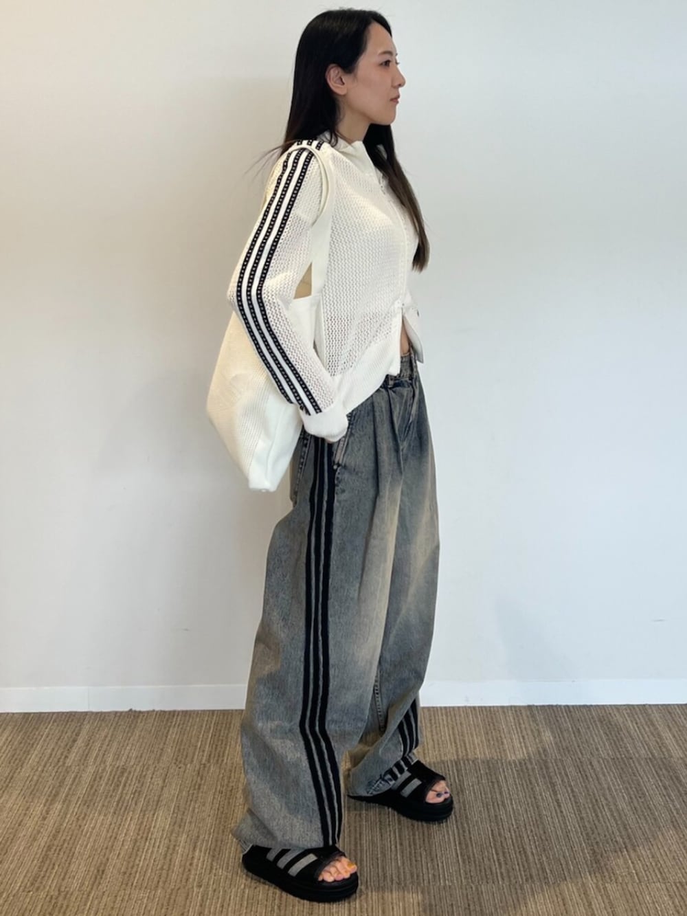 ホワイト系のジャージ、ブラウン系のデニムパンツ、ホワイト系のトートバッグを着用したレディースの春コーディネートの2枚目の写真