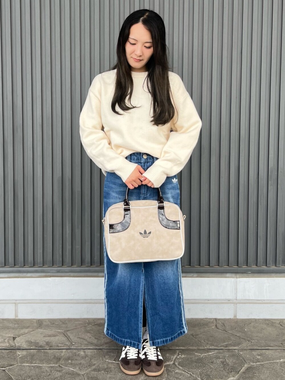ベージュ系のショルダーバッグ、ホワイト系のニット/セーター、ブルー系のデニムスカートを着用したレディースの秋コーディネートの2枚目の写真