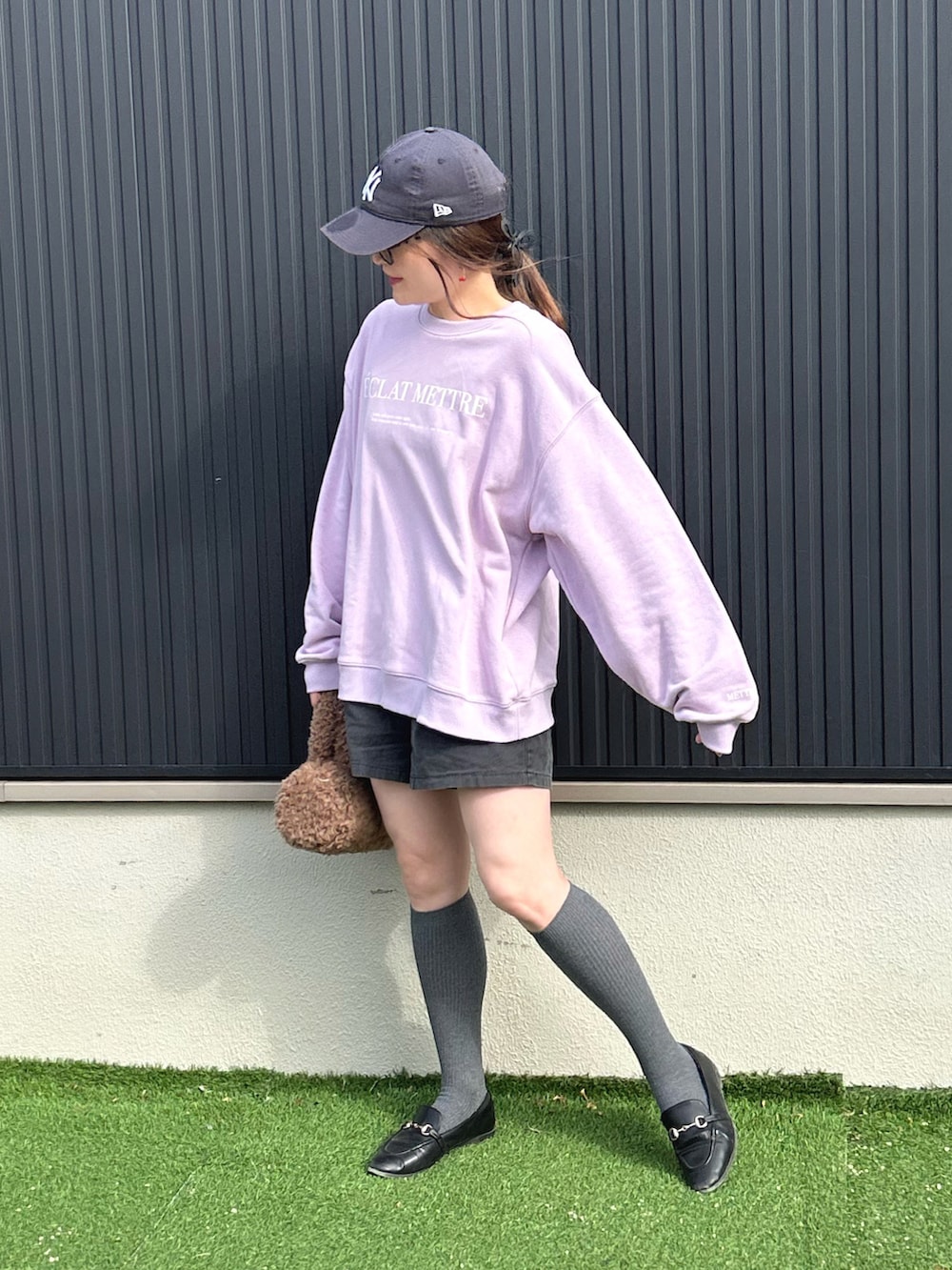 パープル系のスウェット、ブラウン系のショルダーバッグ、ブラック系のその他パンツを着用したレディースの冬コーディネートの2枚目の写真