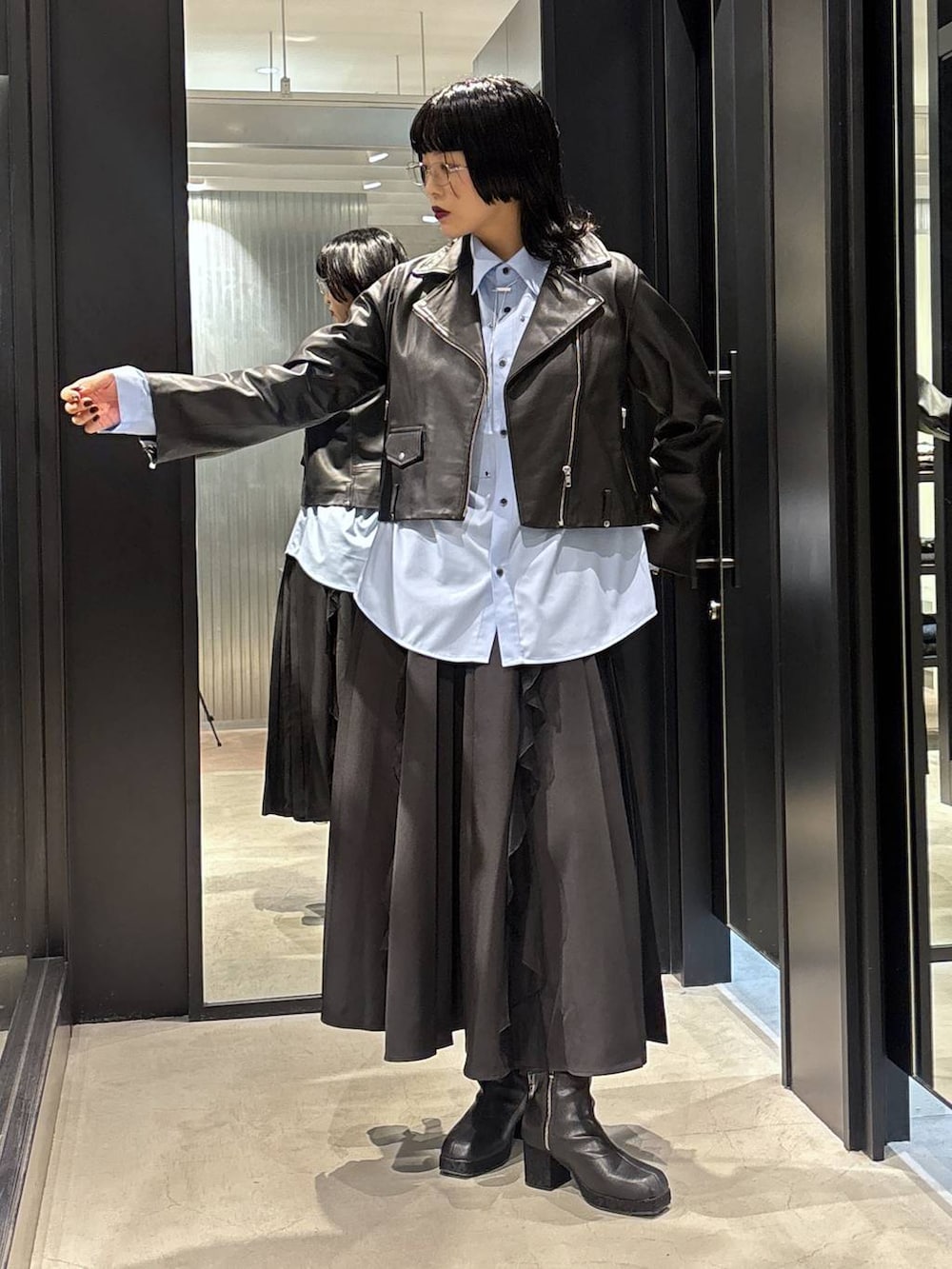 ブラック系のスカート、ブラック系のライダースジャケット、ブラック系のブーツを着用したレディースの秋コーディネートの3枚目の写真