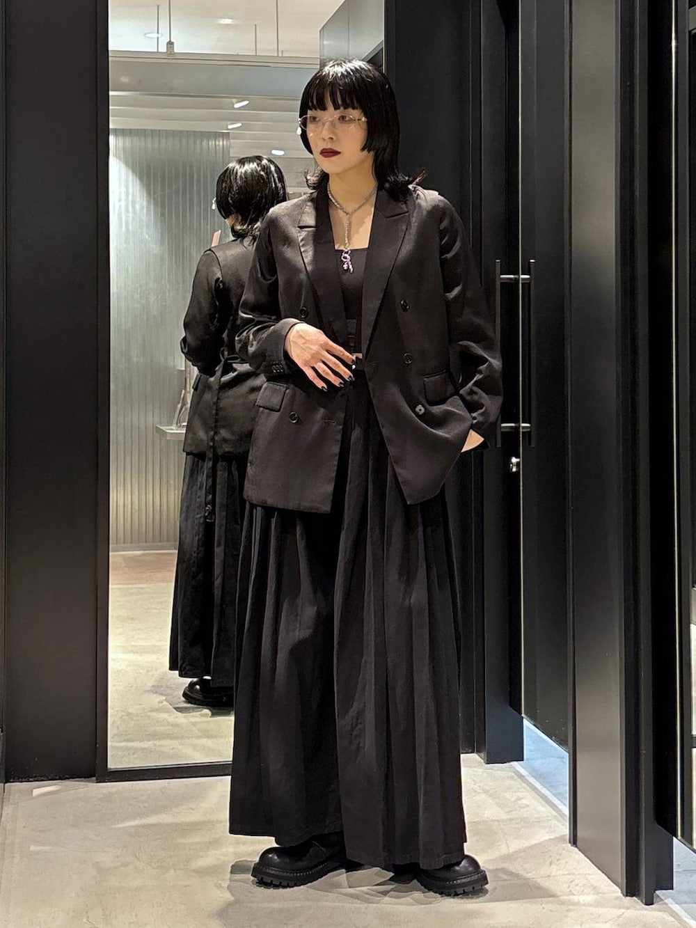 ブラック系のテーラードジャケット、ブラック系のデニムパンツ、ブラック系のブーツを着用したレディースの秋コーディネートの2枚目の写真