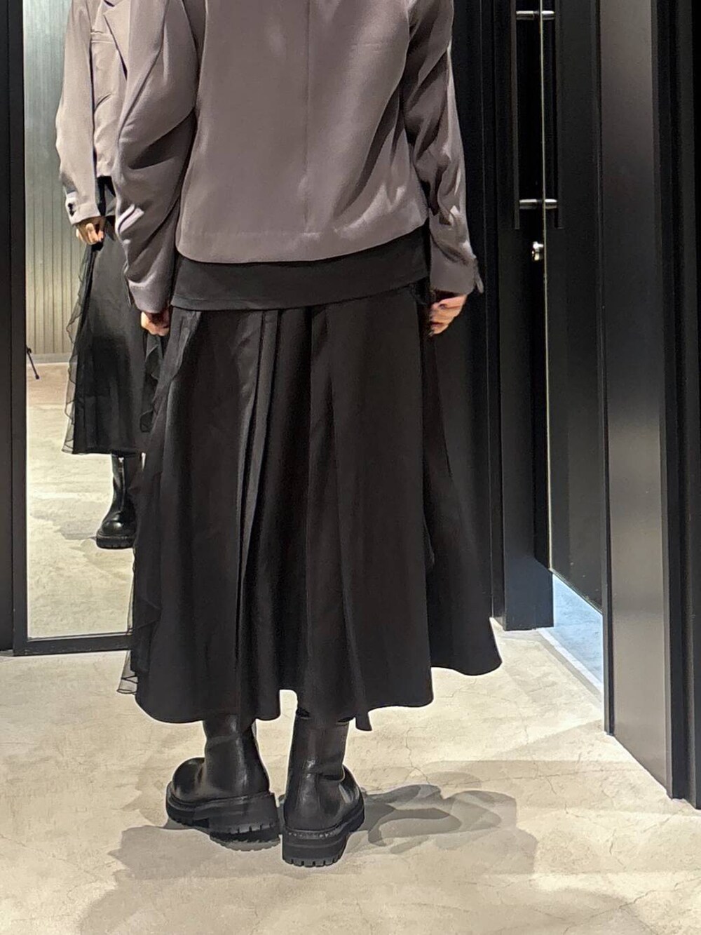 グレー系のテーラードジャケット、ブラック系のスカート、ブラック系のブーツを着用したレディースの秋コーディネートの5枚目の写真