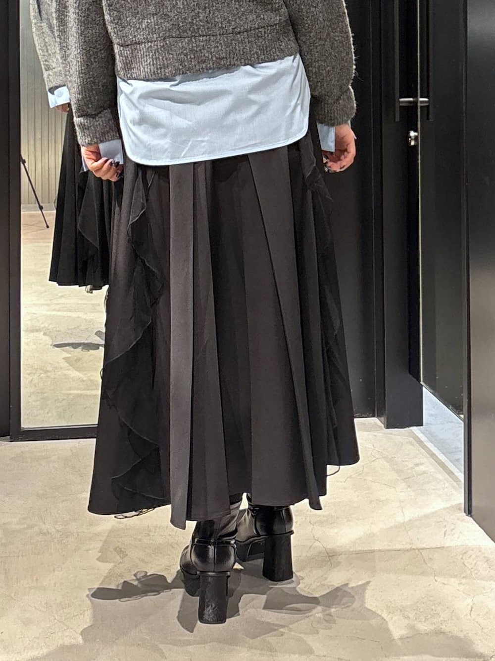 ブラック系のスカート、ブラック系のブーツ、グレー系のニット/セーターを着用したレディースの秋コーディネートの5枚目の写真