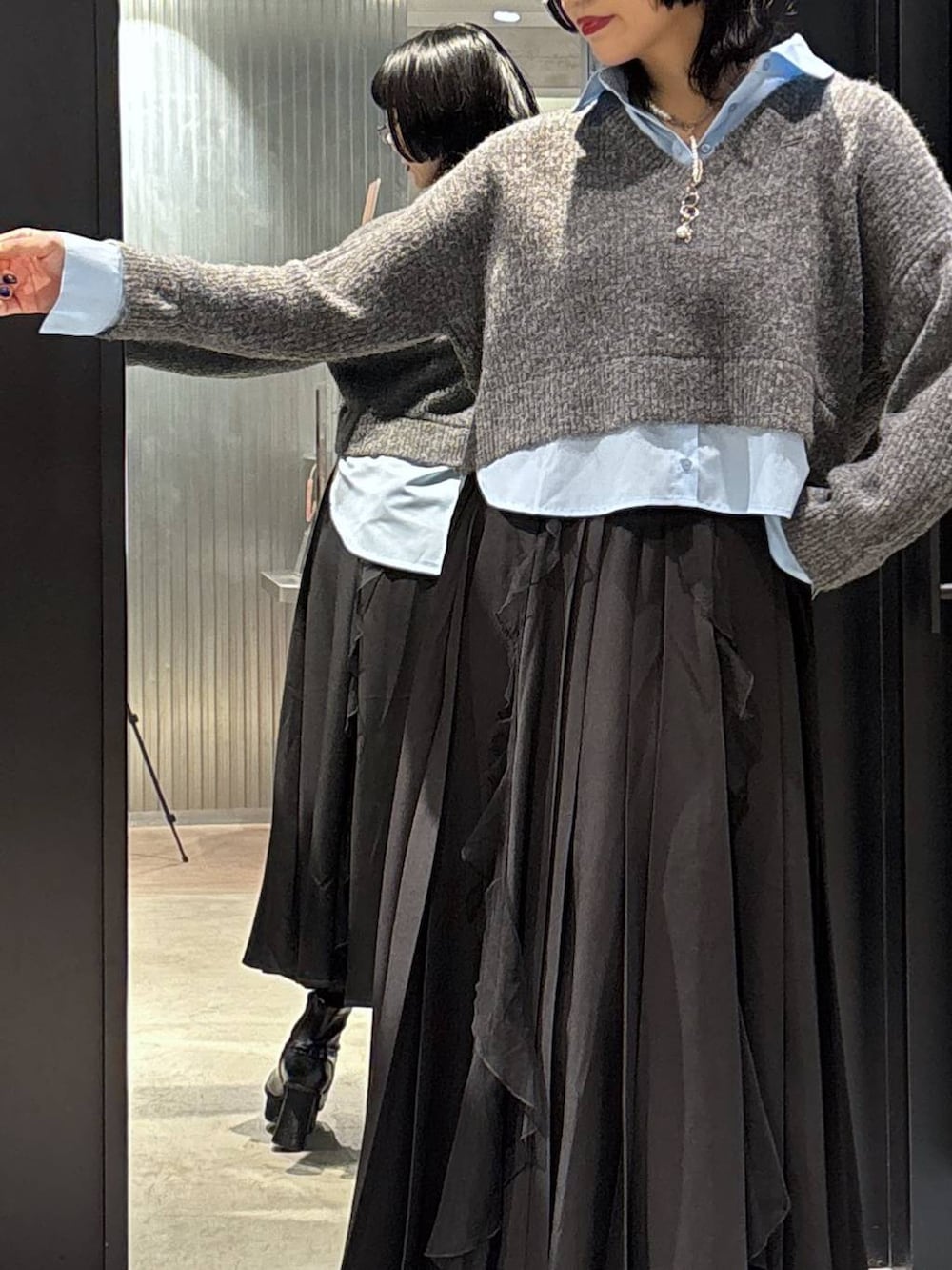 ブラック系のスカート、ブラック系のブーツ、グレー系のニット/セーターを着用したレディースの秋コーディネートの4枚目の写真