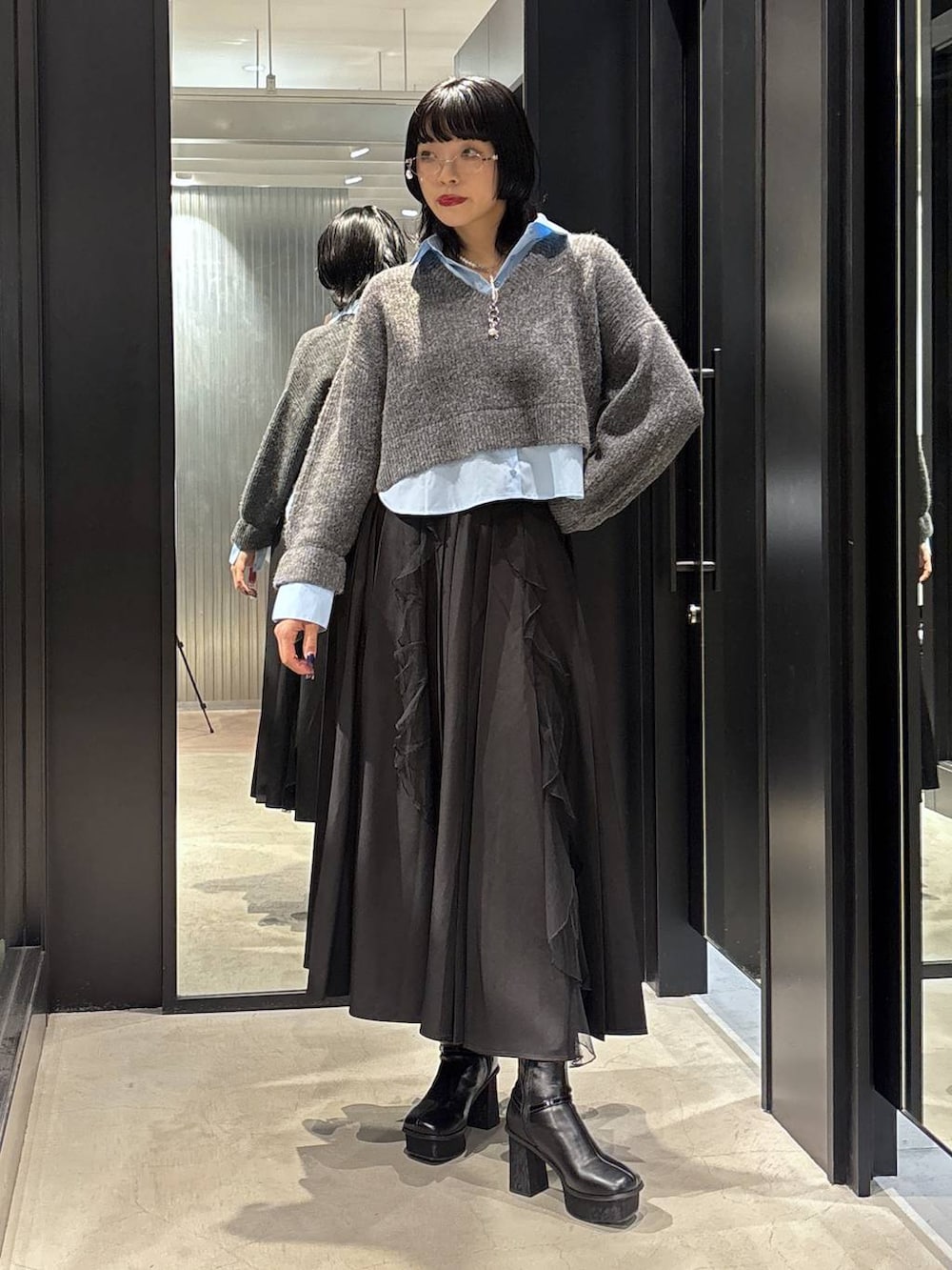 ブラック系のスカート、ブラック系のブーツ、グレー系のニット/セーターを着用したレディースの秋コーディネートの2枚目の写真