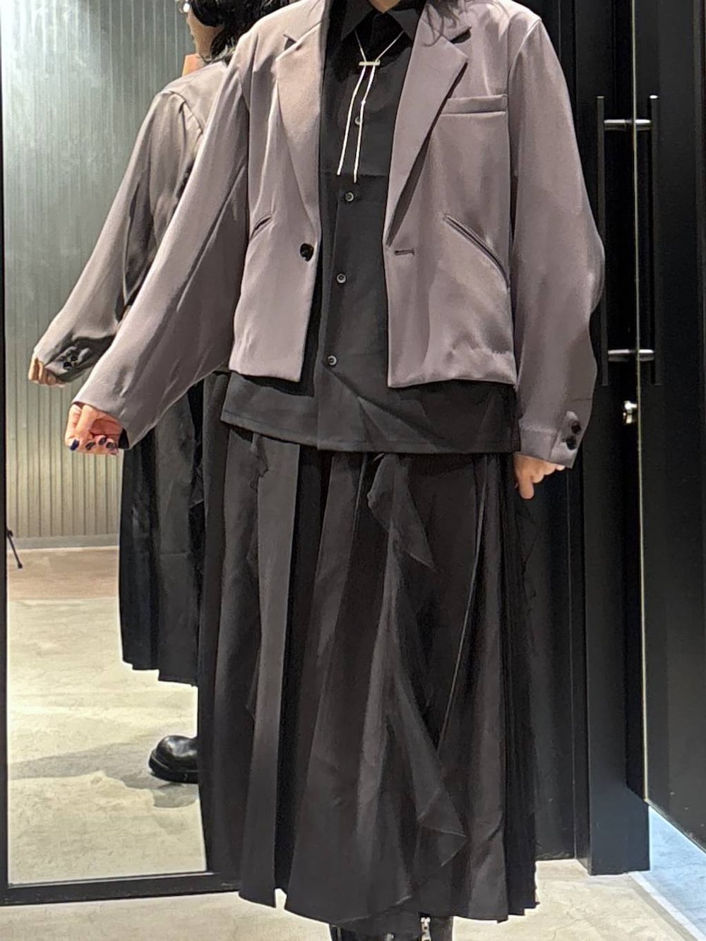 グレー系のテーラードジャケット、ブラック系のスカート、ブラック系のブーツを着用したレディースの秋コーディネートの4枚目の写真