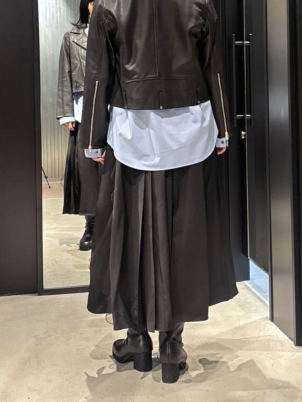 ブラック系のスカート、ブラック系のライダースジャケット、ブラック系のブーツを着用したレディースの秋コーディネートの5枚目の写真