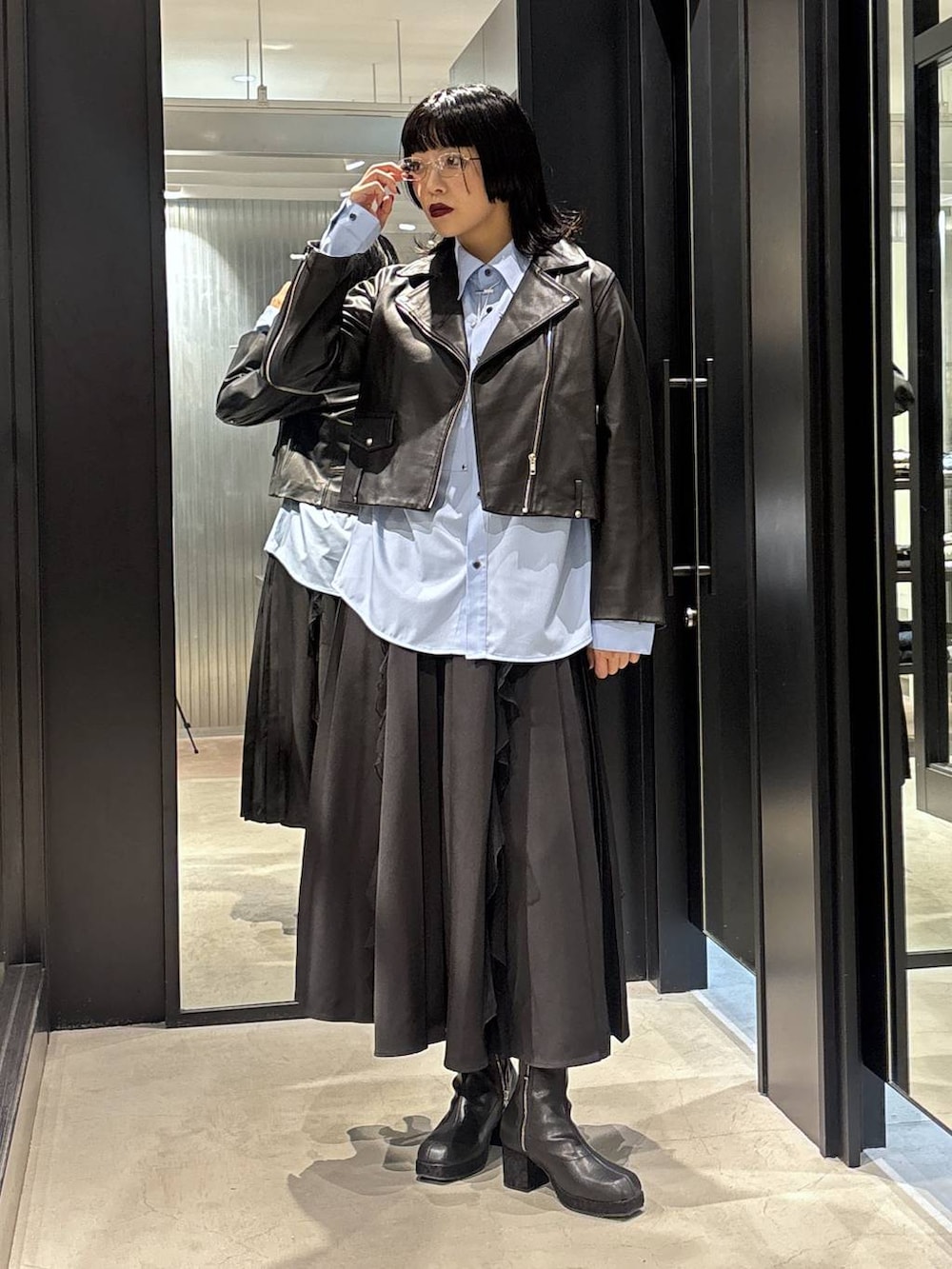 ブラック系のスカート、ブラック系のライダースジャケット、ブラック系のブーツを着用したレディースの秋コーディネートの2枚目の写真