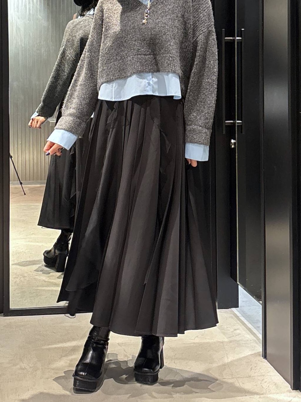 ブラック系のスカート、ブラック系のブーツ、グレー系のニット/セーターを着用したレディースの秋コーディネートの3枚目の写真