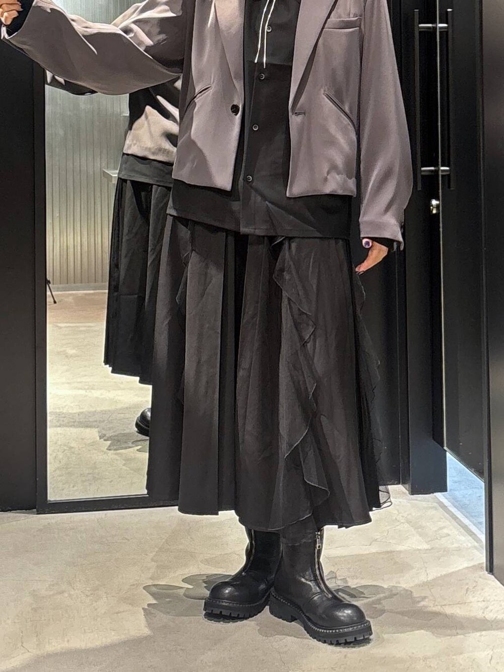 グレー系のテーラードジャケット、ブラック系のスカート、ブラック系のブーツを着用したレディースの秋コーディネートの3枚目の写真