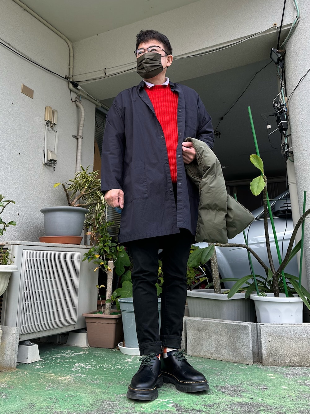 ブラック系のデニムパンツ、レッド系のニット/セーター、パープル系のポロシャツを着用したメンズの冬コーディネートの2枚目の写真