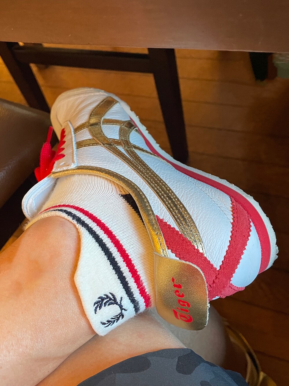 レッド系のポロシャツ、ブラック系のパンツ、ホワイト系のスニーカーを着用したメンズの夏コーディネートの2枚目の写真