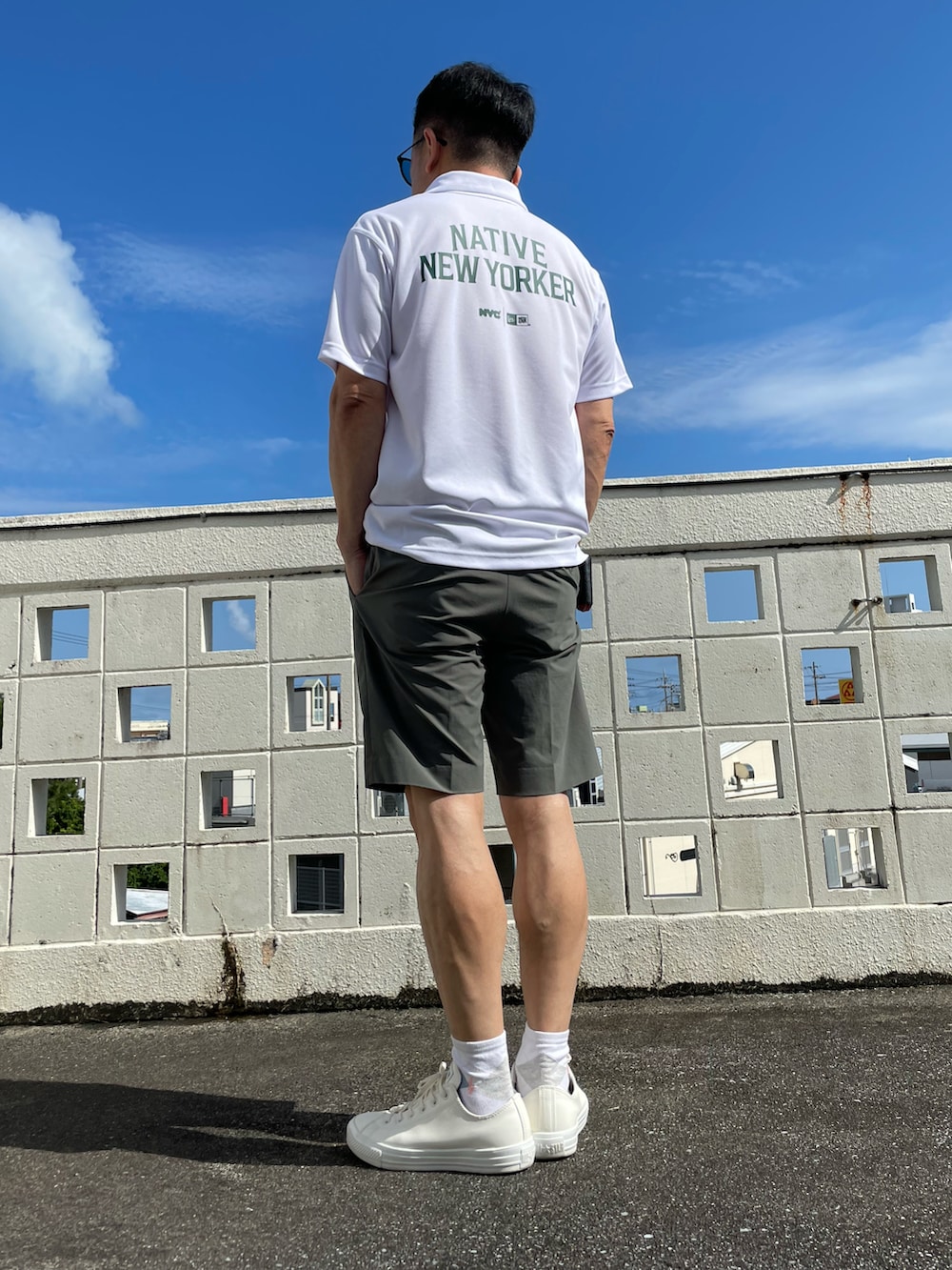 ホワイト系のポロシャツ、グリーン系のパンツ、ホワイト系のレインシューズを着用したメンズの春コーディネートの2枚目の写真