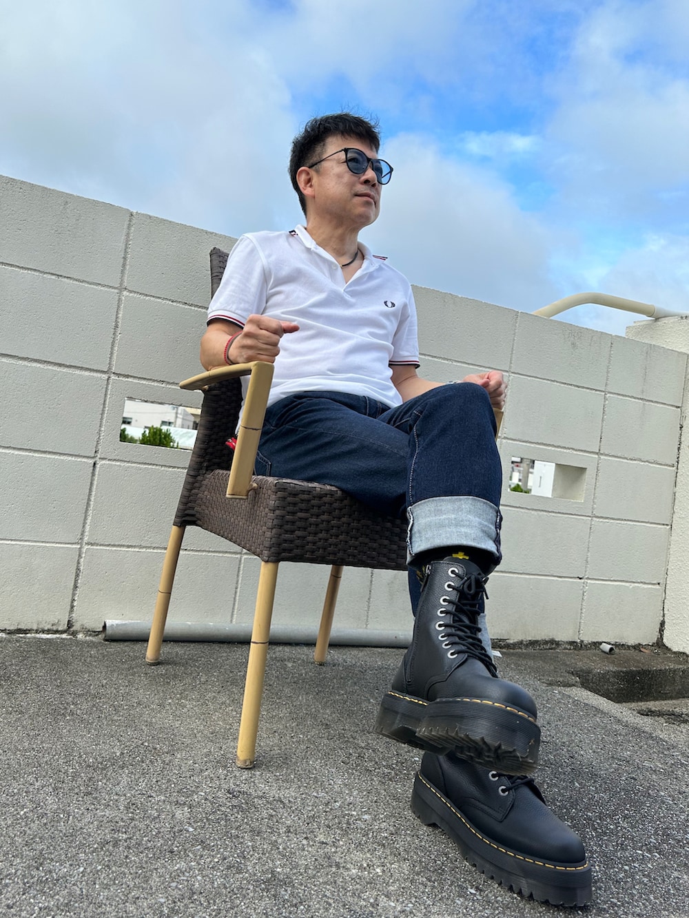 ブルー系のデニムパンツ、ホワイト系のポロシャツ、ブラック系のブーツを着用したメンズの秋コーディネートの2枚目の写真