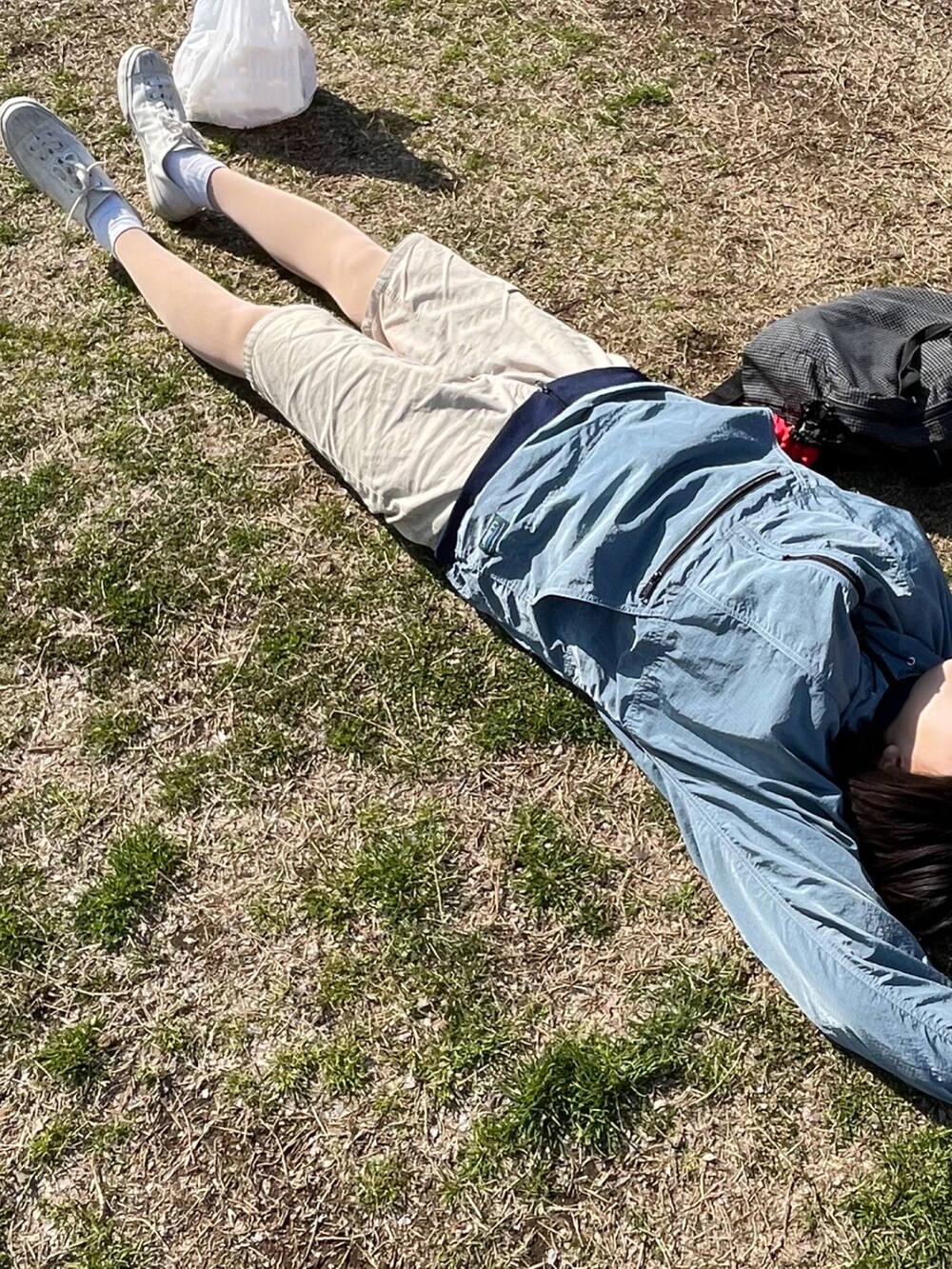 ベージュ系のパンツ、ブルー系のマウンテンパーカー、ホワイト系のスニーカーを着用したレディースの春コーディネートの2枚目の写真