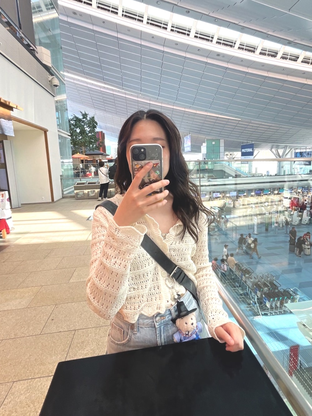 ブルー系のデニムパンツ、ブルー系のスニーカー、ブラック系のバッグを着用したレディースの夏コーディネートの2枚目の写真