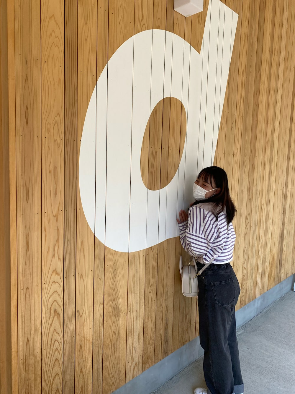 ブラック系のデニムパンツ、パープル系のTシャツ/カットソー、ホワイト系のバッグを着用したレディースの冬コーディネートの2枚目の写真