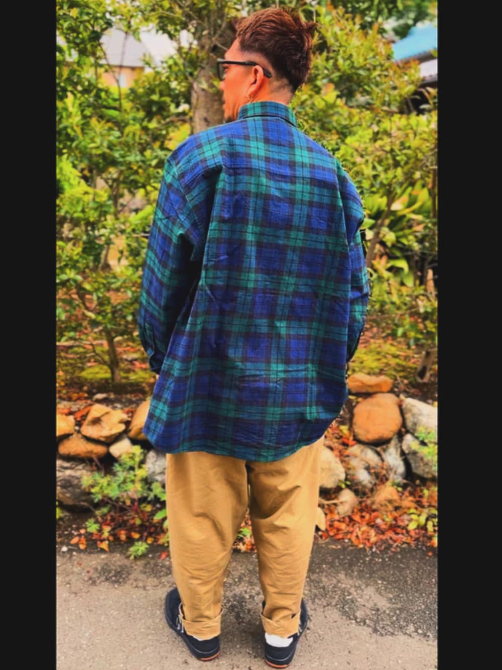 グリーン系のシャツ/ブラウス、ベージュ系のチノパンツ、ブラック系のスニーカーを着用したメンズの春コーディネートの3枚目の写真