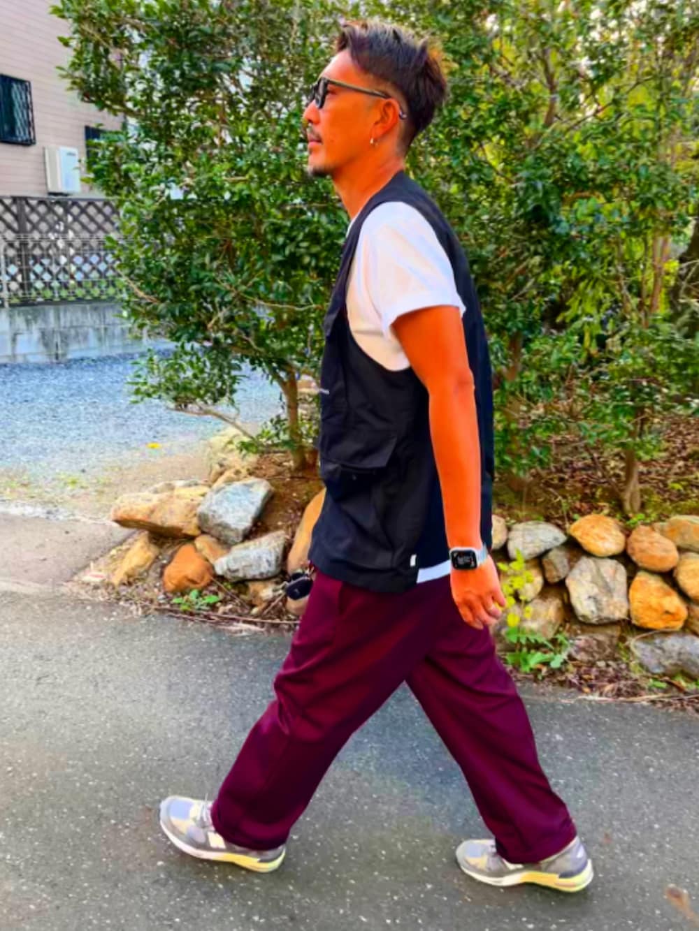 ホワイト系のTシャツ/カットソー、ブラック系のベスト、レッド系のチノパンツを着用したメンズの秋コーディネートの5枚目の写真