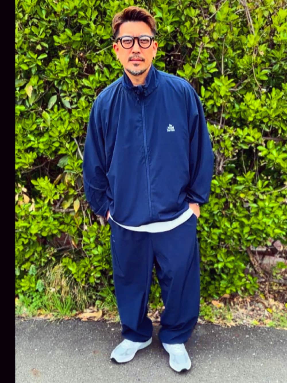 ブルー系のナイロンジャケット、ブルー系のその他パンツ、グレー系のスニーカーを着用したメンズの春コーディネートの2枚目の写真