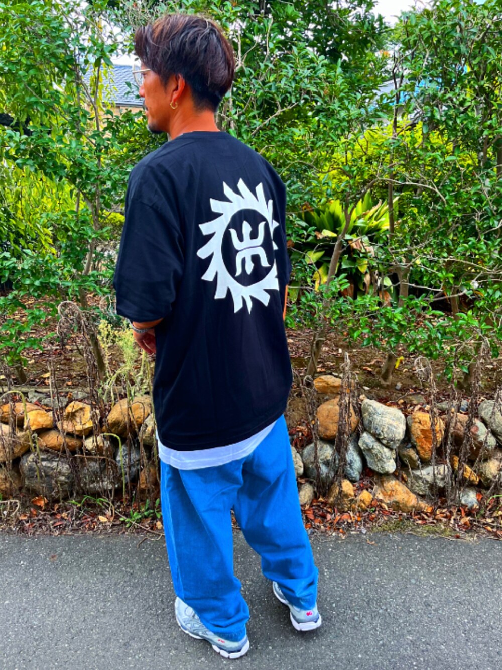 ブラック系のTシャツ/カットソー、ブルー系のデニムパンツ、グレー系のスニーカーを着用したメンズの秋コーディネートの5枚目の写真