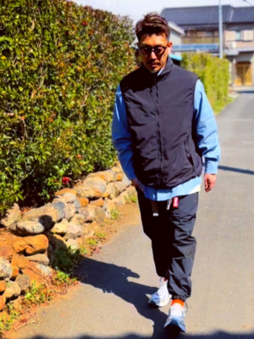 ブラック系のダウンベスト、ブルー系のシャツ/ブラウス、ブラック系のその他パンツを着用したメンズの春コーディネートの3枚目の写真