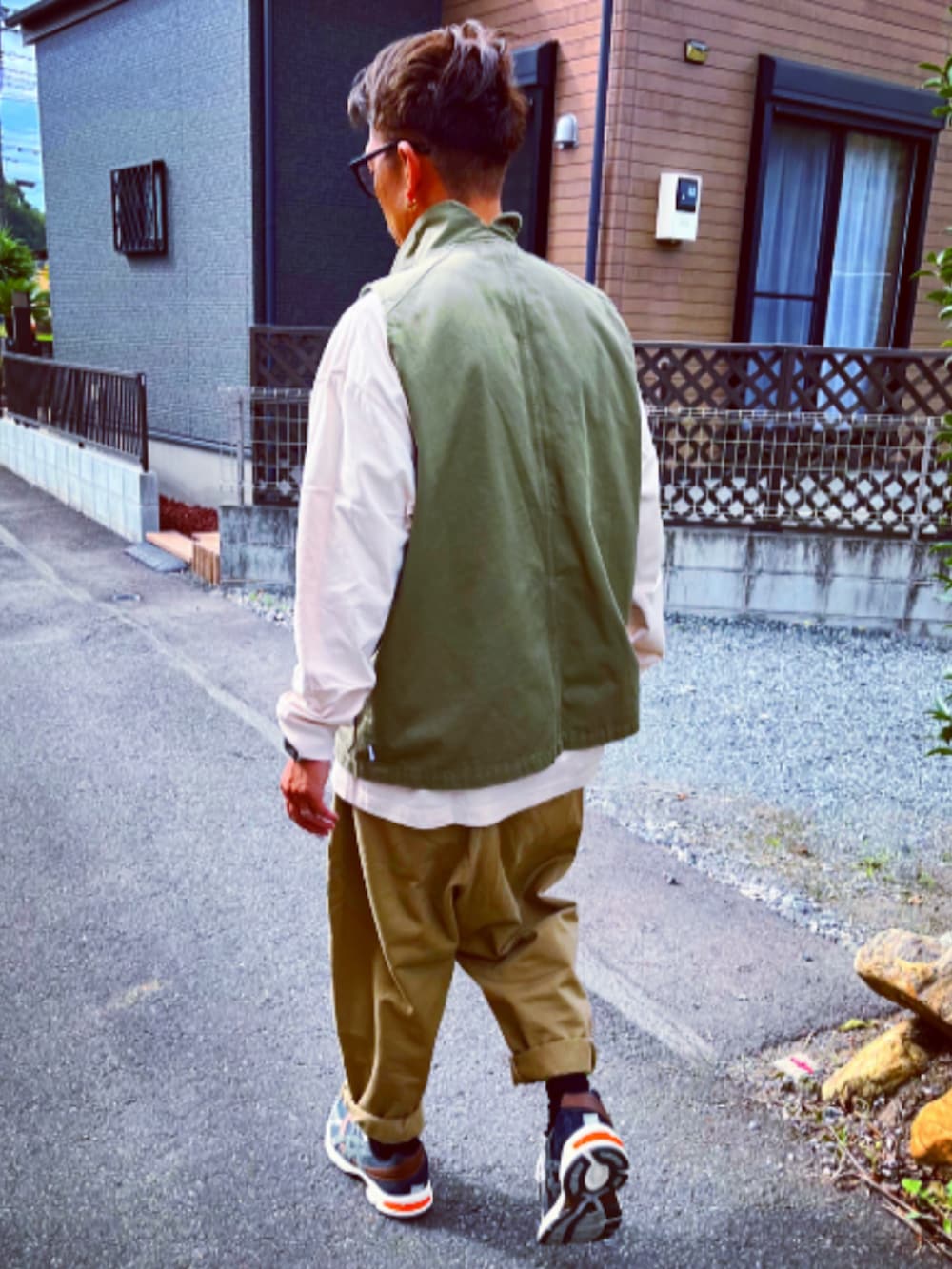 ホワイト系のTシャツ/カットソー、グリーン系のベスト、ベージュ系のチノパンツを着用したメンズの秋コーディネートの5枚目の写真