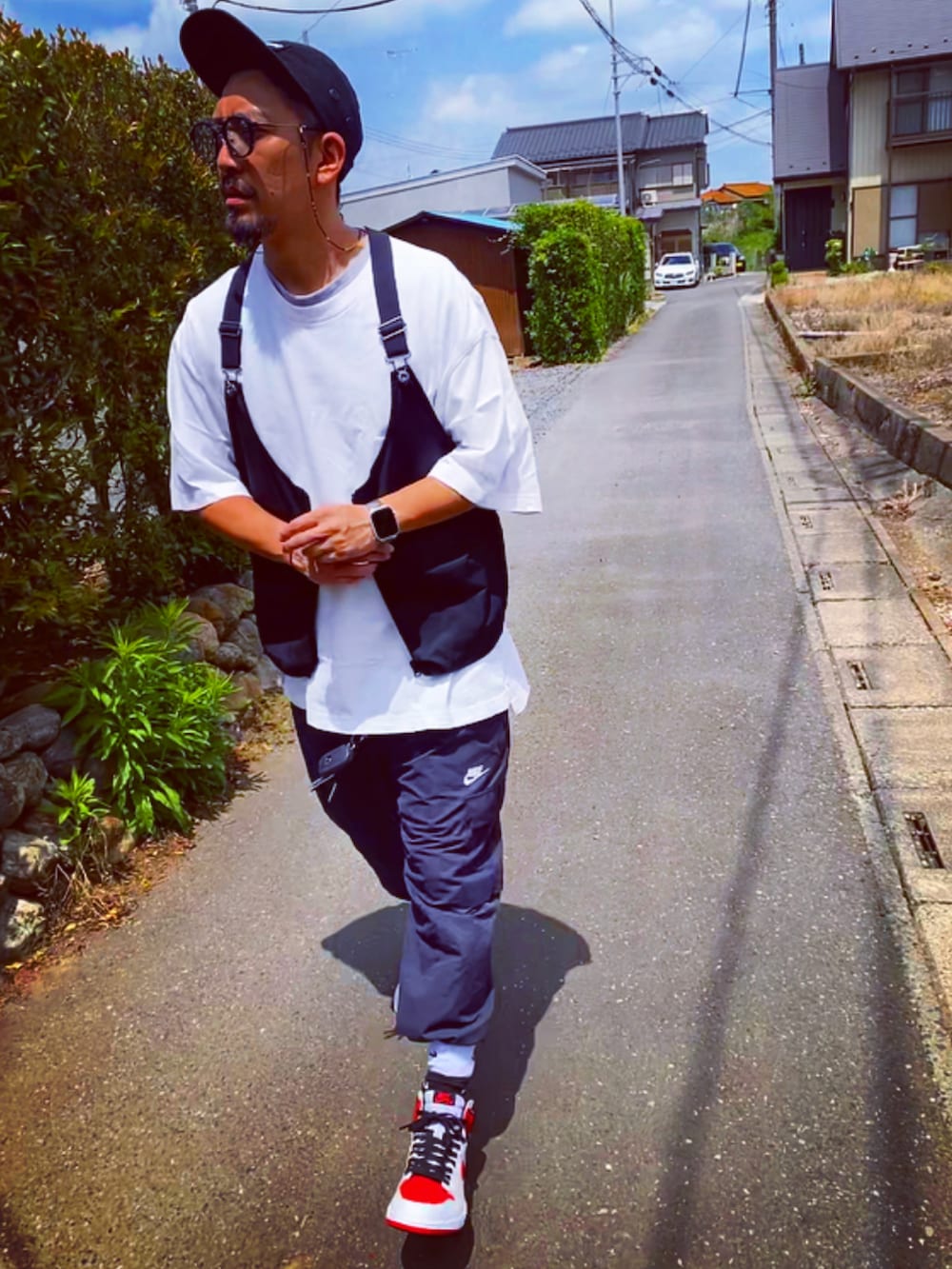 ブラック系のベスト、ホワイト系のTシャツ/カットソー、ブラック系のカーゴパンツを着用したメンズの春コーディネートの2枚目の写真