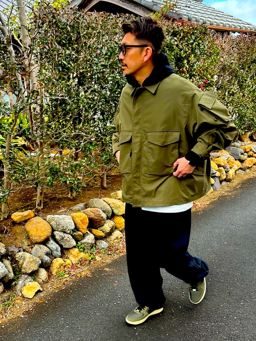 ブラック系のパーカー、グリーン系のミリタリージャケット、ベージュ系のスウェットパンツを着用したメンズの冬コーディネートの2枚目の写真